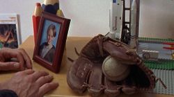 Some stuff on the chest of drawers, like a baseball glove and ball, a picture of Charlie, and a Space Shuttle made with Lego.